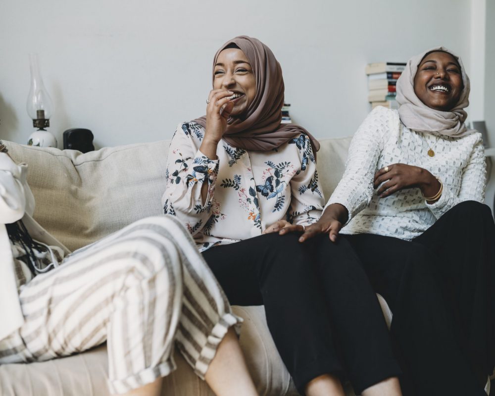 Three women sitting on the couch laughing