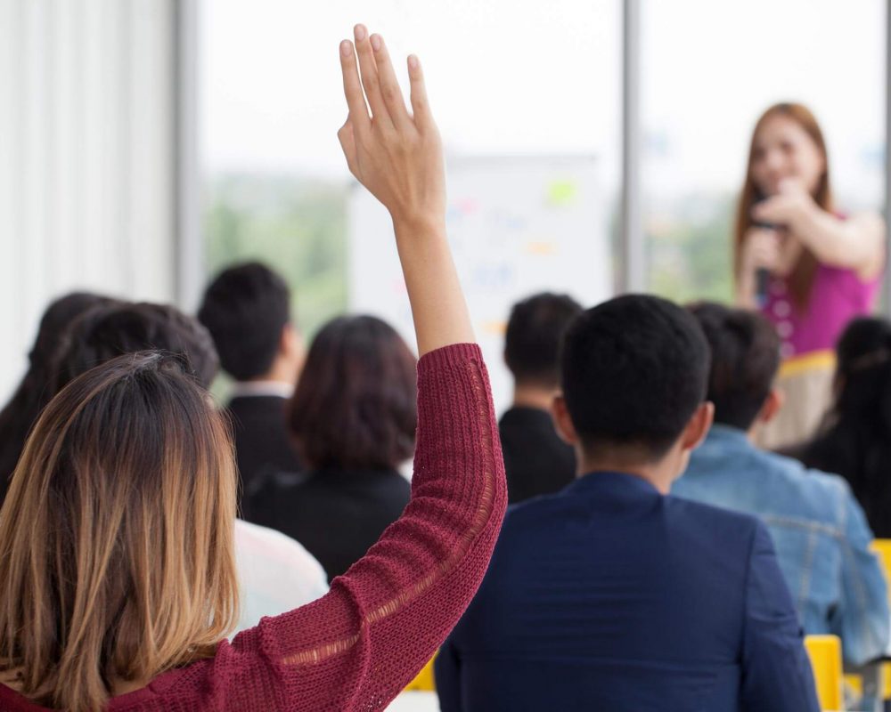 Woman with hand up to ask question in a group